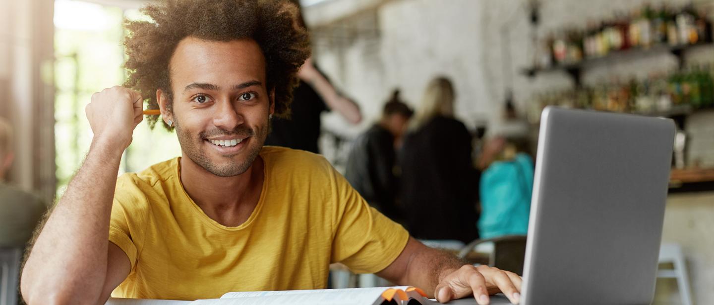 a student working at a computer smiles at the camera